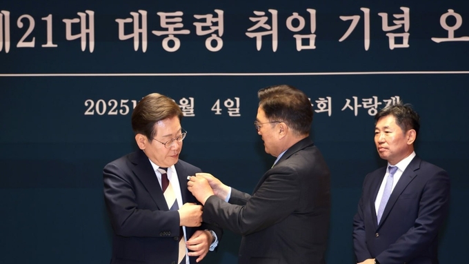 우원식국회의장이 4일(수) 국회 사랑재에서 열린 제21대 대통령 취임 기념 오찬에서 이재명 대통령에게 '진관사 태극기'를 달아주고 있다. 진관사 태극기는 3·1운동이 일어나고 대한민국 임시정부가 수립된 1919년 기미년에 제작된 것으로 추정된다. 일장기 위에 덧그려진 태극기로 일장기 거부와 독립운동 정신의 상징을 담고 있다.<br>
<br>
국회제공